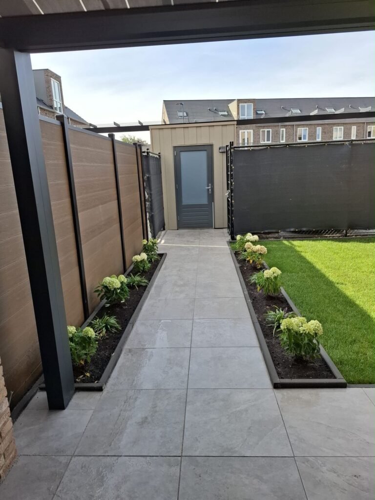 Achtertuin met overkapping, tegelpad, borders en gazon door Excellent Tuin Onderhoud