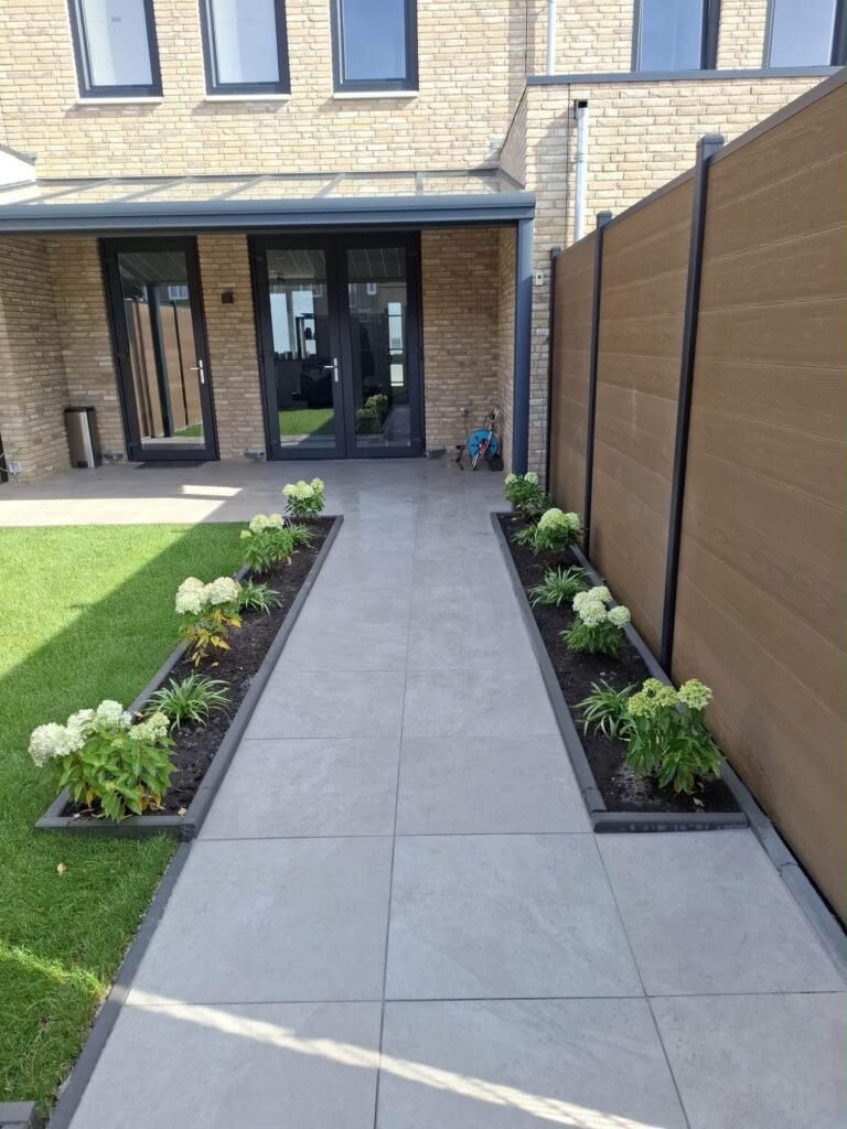 Strak tegelpad met borders en gazon in een nieuw aangelegde achtertuin door Excellent Tuin Onderhoud