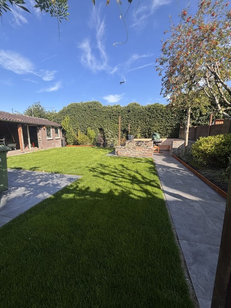 Lange achtertuin met gazon en tegelpad door Excellent Tuin Onderhoud