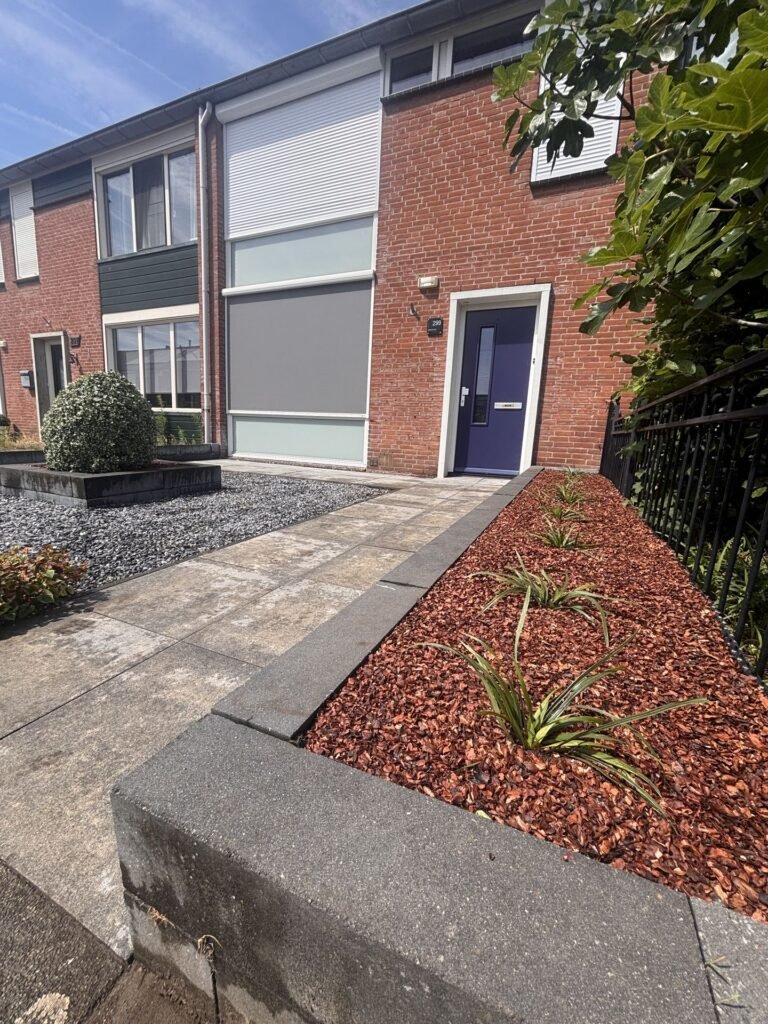 Voortuin met borders, boomschors en tegelpad door Excellent Tuin Onderhoud