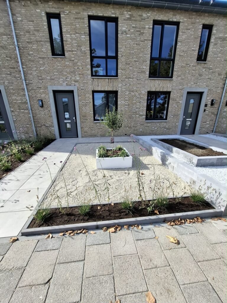 Nieuw aangelegde voortuinen met witte plantenbakken en siergrind door Excellent Tuin Onderhoud