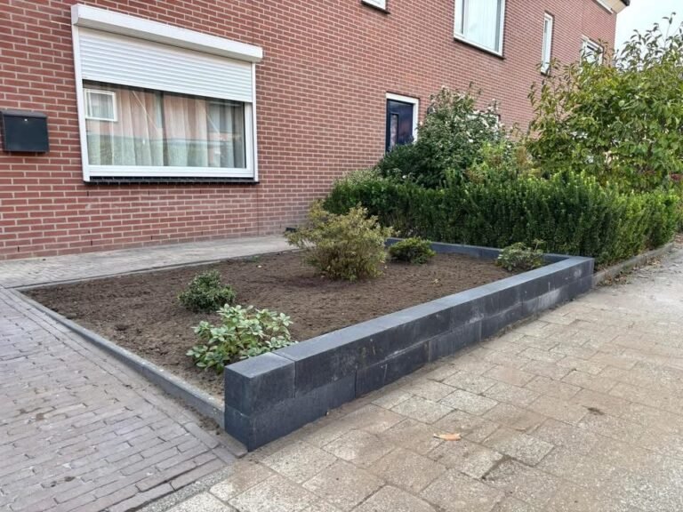 Voortuin met plantvak en keerwand van stapelblokken door Excellent Tuin Onderhoud